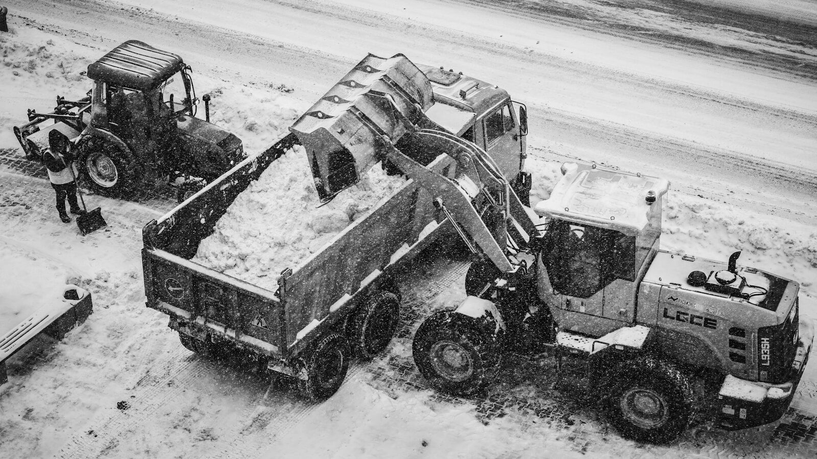 Construction vehicles clearing snow from a street.